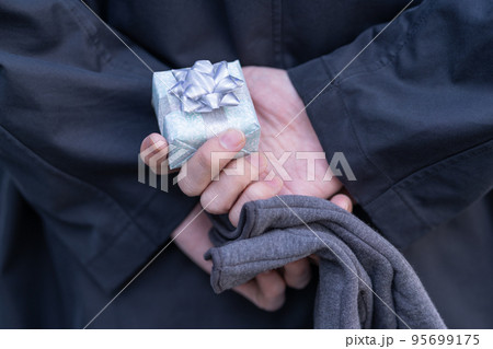 プレゼントの箱を後手に持つ男性の手のアップ 95699175