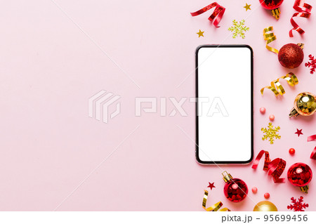 Christmas online shopping from home phone with blank white display top view. smart mobile with copy space on colored background with Christmas decorations balls,. Winter holidays sales background 95699456