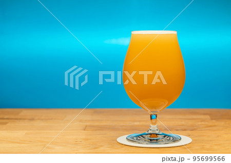 Full tulip glass of NEIPA ale beer on a table Full tulip glass of NEIPA ale beer on a table 95699566