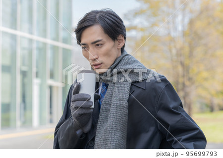 マフラーと手袋をしてタンブラーを手に持つ男性のポートレート 95699793
