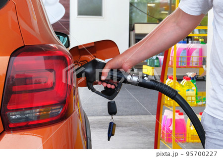 Pumping gasoline fuel in orange car at a gas station. To fill car with fuel in petrol station. Petrol station pump. Close up. Pumping gasoline fuel in orange car at a gas station. To fill car with fuel in petrol station. Petrol station pump. Close up. 95700227
