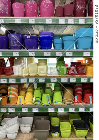 Variety of colorful flower pots are sold at the store. Rows of different pots for indoor plants on shelves in a mall. Vertical view. 95701023