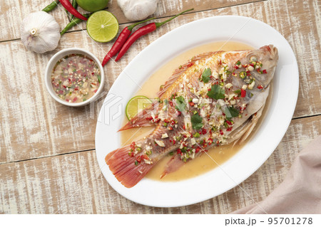 Steamed Red Tilapia Fish with Spicy Lemon Sauce in white plate.Top view Steamed Red Tilapia Fish with Spicy Lemon Sauce in white plate.Top view 95701278