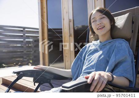 屋外サウナの前でサウナポンチョを着て外気浴をするサウナ女子 屋外サウナの前でサウナポンチョを着て外気浴をするサウナ女子 95701411