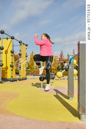 Outdoor training. Weight lost concept. Young woman doing fitness exercises at street public sports ground. Sunny autumn day. Sport, health, plans, body positive Outdoor training. Weight lost concept. Young woman doing fitness exercises at street public sports ground. Sunny autumn day. Sport, health, plans, body positive 95701618