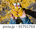 Female hand in autumn park enjoying autumn and holding a leaf. 95701768