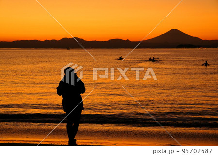 秋の夕暮れの逗子海岸でたたずむ女性のシルエット 95702687