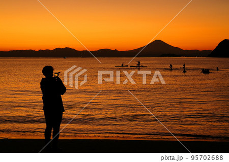 秋の夕暮れの逗子海岸でたたずむ女性のシルエット 95702688