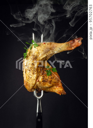 Oven baked chicken thigh with parsley on a fork. Menu or recipe concept for restaurant or hotel on black background 95702763