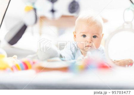 Cute baby boy playing with hanging toys arch on mat at home Baby activity and play center for early infant development. Baby playing at home 95703477
