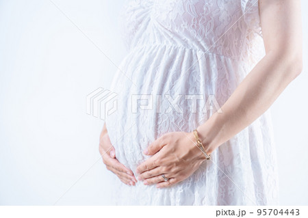 マタニティワンピースでお腹をささえる妊婦 白背景（本物の臨月妊婦さんを撮影） 95704443