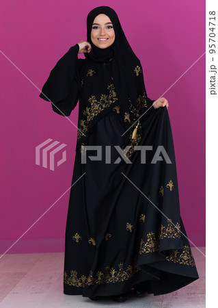 beautiful muslim woman in fashinable dress with hijab isolated on modern pink background representing concept of modern islam and ramadan kareem 95704718
