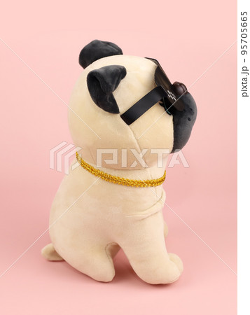Plush soft beige black pug dog toy with sunglasses isolated on pink background. Side view, close-up 95705665