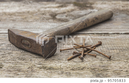 Old rusty hammer and nails on an unpainted wooden table Old rusty hammer and nails on an unpainted wooden table 95705833