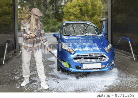 the women herself at the car wash washes the car with a brush the women herself at the car wash washes the car with a brush 95711858