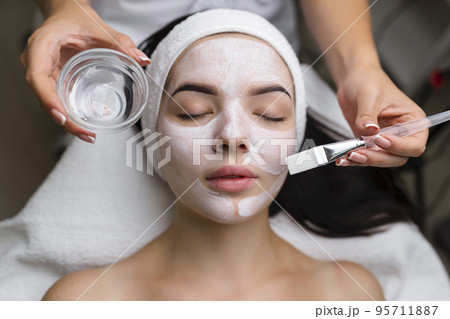 Close-up shot of a woman getting facial treatment with clay mask. Cosmetology and spa Close-up shot of a woman getting facial treatment with clay mask. Cosmetology and spa 95711887