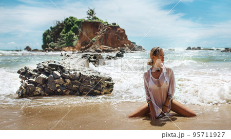 Beautiful young woman in sexy bikini standing at sea beach 95711927