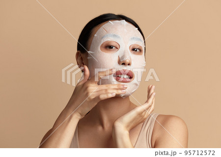 Woman Face Mask. Portrait Of Beautiful Girl Applying Cosmetic White Textile Mask 95712572