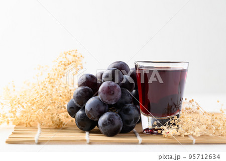 Black grape and juice in glass on white background, healthy drink 95712634