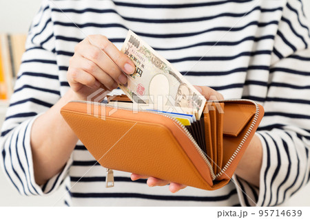 財布からお金を出すカジュアル姿のミドル女性 95714639