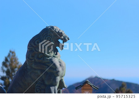 青空と山々を背景にした神社の狛犬 95715325