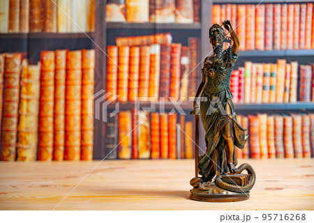 Lawyer office. Statue of Justice with scales close-up against the backdrop of a wall of books or a library . Legal law, advice and justice concept Lawyer office. Statue of Justice with scales close-up against the backdrop of a wall of books or a library . Legal law, advice and justice concept 95716268