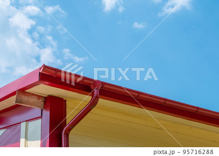 Red gutter on the roof top of house. 95716288
