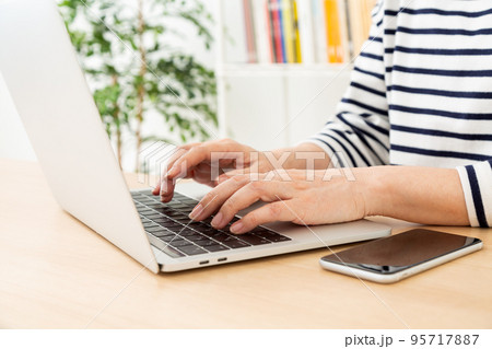 部屋でパソコンを操作するカジュアル姿のミドル女性 部屋でパソコンを操作するカジュアル姿のミドル女性 95717887