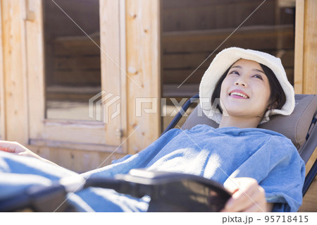 屋外サウナの前でサウナポンチョを着て外気浴をするサウナ女子 インフィニティチェア 屋外サウナの前でサウナポンチョを着て外気浴をするサウナ女子 インフィニティチェア 95718415