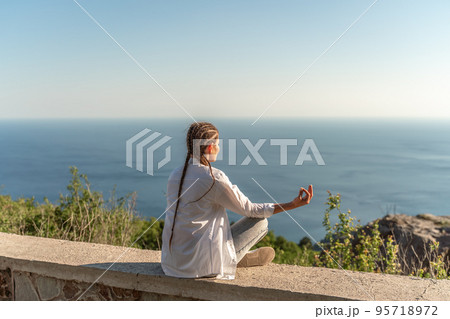 Profile of a woman doing yoga in the top of a cliff in the mountain. Woman meditates in yoga asana Padmasana 95718972