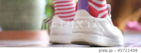 Man in striped socks putting on white sneakers with shoehorn closeup Man in striped socks putting on white sneakers with shoehorn closeup 95721408