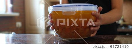 Housewife holding plastic container with soup in her hands closeup Housewife holding plastic container with soup in her hands closeup 95721410
