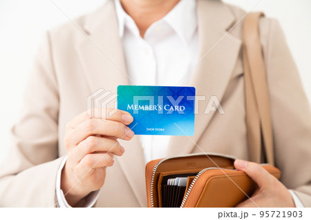 メンバーズカードを持つスーツ姿のミドル女性 95721903