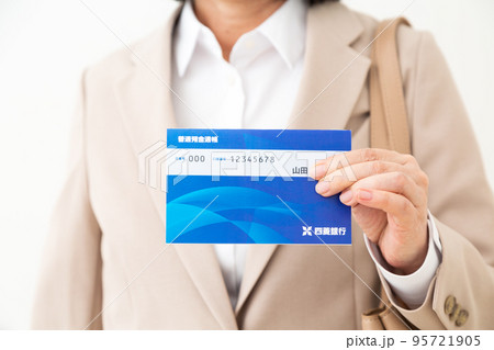 銀行通帳を持つスーツ姿のミドル女性 95721905