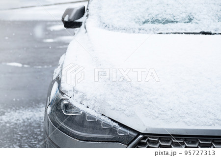 First snow covered car, close up. Car parked on the street at snowy day. First snow covered car, close up. Car parked on the street at snowy day. 95727313