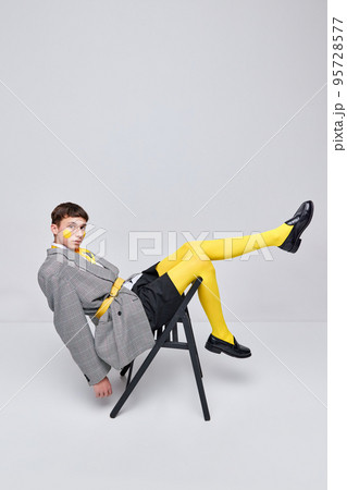 Portrait of stylish boy posing in jacket, blazer and yellow tights isolated over grey background. Casual and bright 95728577