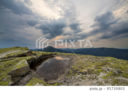 Blue sky reflected in small lake on rocky mountain peak on blue mountain range background at dawn. Blue sky reflected in small lake on rocky mountain peak on blue mountain range background at dawn. 95730803