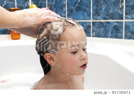 Mom's hands washing little girly's head in the bathroom. The symbol of purity and hygiene education. 95730971