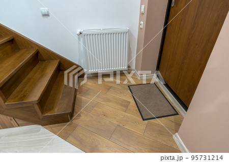 Interior of a house or appartment hallway with oak wooden stairs and room doors. 95731214