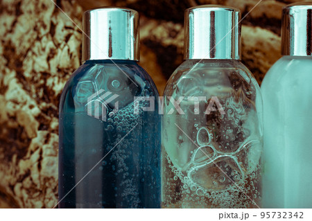 Plastic cosmetic bottles with natural cosmetic in travel containers - shower gel, shampoo with bubbles inside, body lotion in miniature containers against a rock background close up. Face body care. Plastic cosmetic bottles with natural cosmetic in travel containers - shower gel, shampoo with bubbles inside, body lotion in miniature containers against a rock background close up. Face body care. 95732342