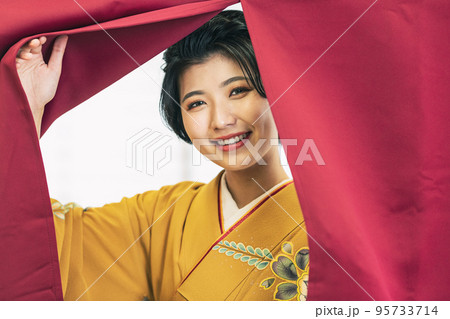暖簾から顔を出す着物姿の女性 95733714