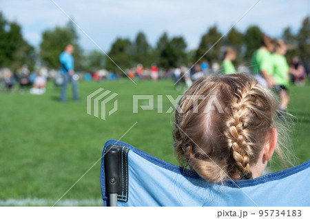 Younger sister watching a soccer game to support her sibling.  95734183