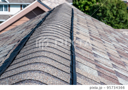 Ridge cap vent installed on a shingle roof for passive attic ventilation on a residential house. Ridge cap vent installed on a shingle roof for passive attic ventilation on a residential house. 95734366