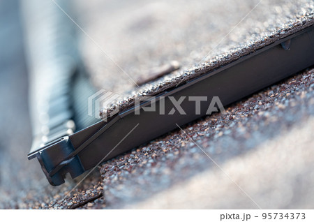 Ridge cap vent installed on a shingle roof for passive attic ventilation on a residential house. Ridge cap vent installed on a shingle roof for passive attic ventilation on a residential house. 95734373