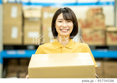 倉庫でダンボールを運ぶ女性スタッフ 倉庫でダンボールを運ぶ女性スタッフ 95734586