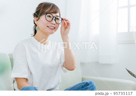 家でソファに座るメガネをかけたアジア人女性 95735117