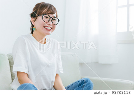 家でソファに座るメガネをかけたアジア人女性 95735118