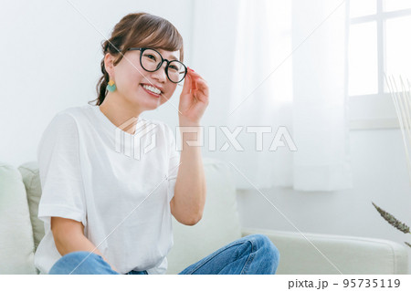 家でソファに座るメガネをかけたアジア人女性 95735119