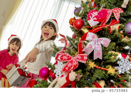 クリスマスツリーの横で遊ぶ姉妹 95735983