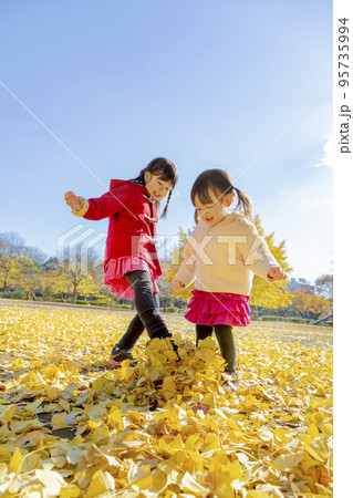 黄葉の公園で遊ぶ姉妹 95735994